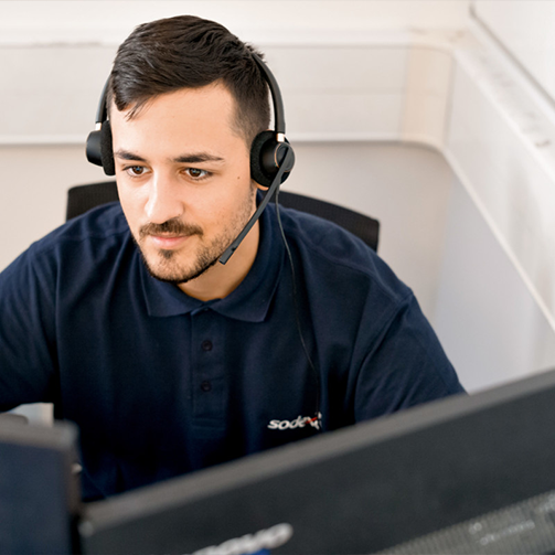 A man wearing a headset and looking at a computer