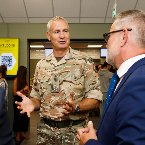 A military talking to a man in a blue suit and tie
