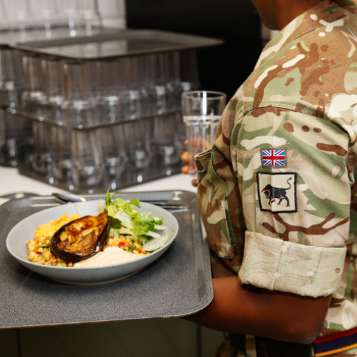 A military woman holding a tray of healthy food