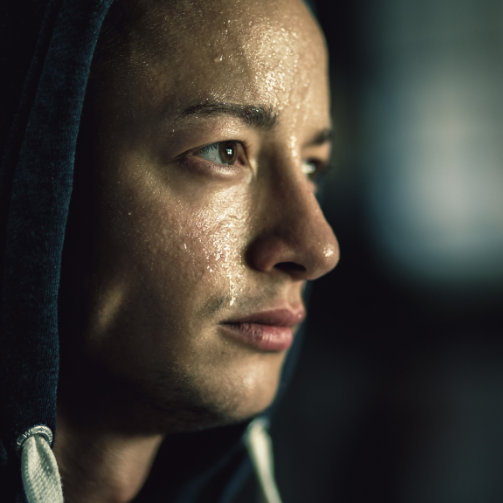 A man wearing a hoodie glances sideways