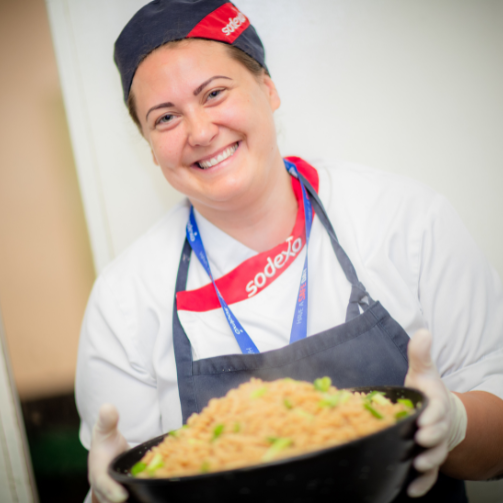 A woman holding a bowl of food, smiling