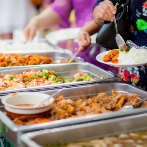 Hands of people with cutlery serving themselves fresh food trays