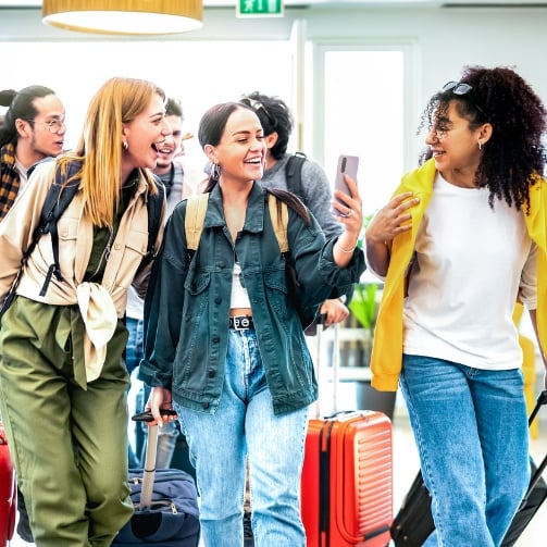 A group of young travelers walking and carrying backpacks and suitcases