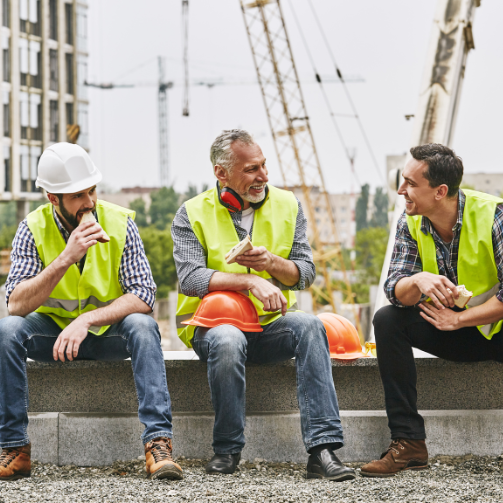 Three industrial workers having a break on a concrete barrier