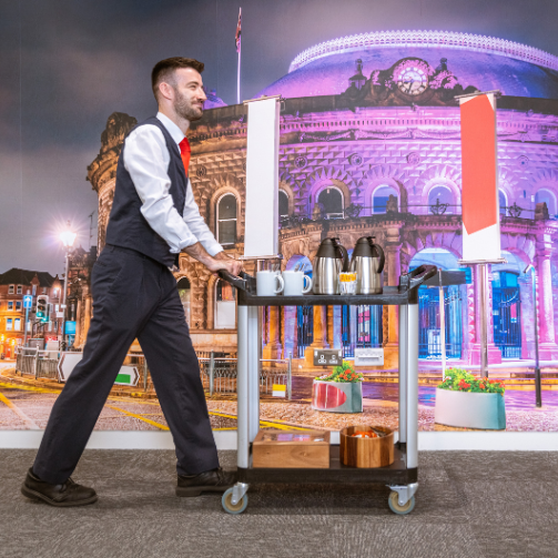A man in uniform pushing a cart with hot drinks. A man in uniform pushing a cart with hot drinks