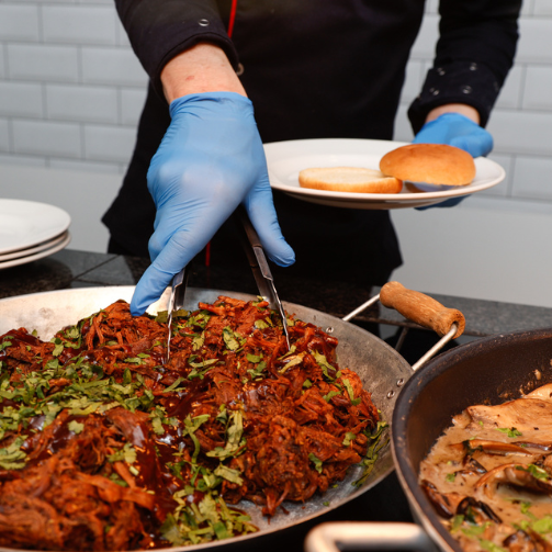 A plate of food being served from a large pan of food