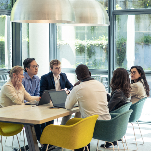 A group of individuals gathered around a table, engaged in conversation and sitting together