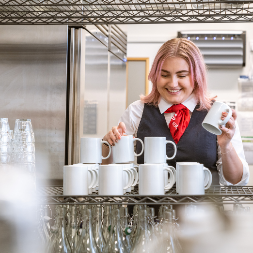  A woman smiling while arranging some mugs
