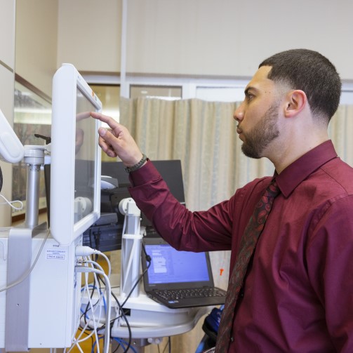 A man is clicking in a screen of medical equipment in a hospital room
