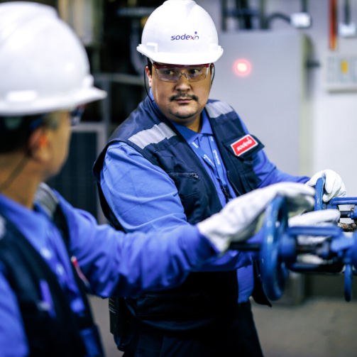 Two men wearing blue hard hats at a construction site