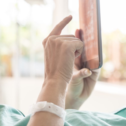 A hand of a patient, clicking on a tablet screen