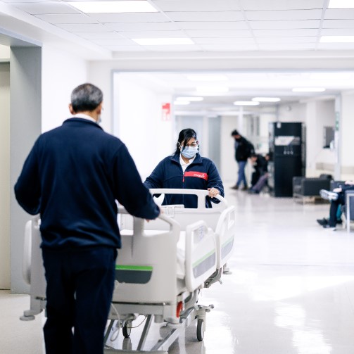 Two porters moving a bed in a hospital corridor
