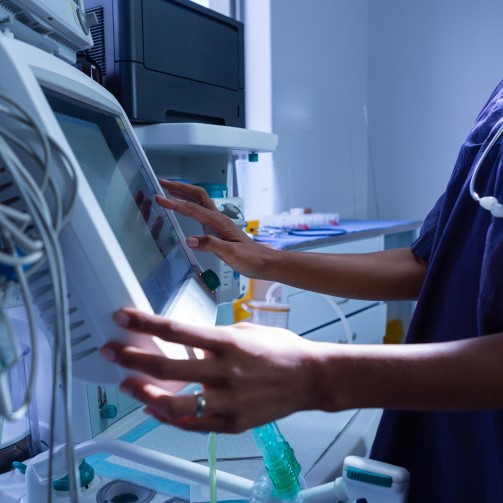 A nurse is interacting with a monitor of a medical equipment