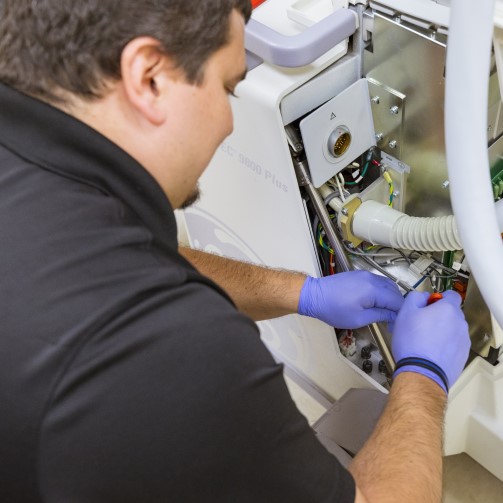 A male worker wearing purple gloves is fixing medical equipment