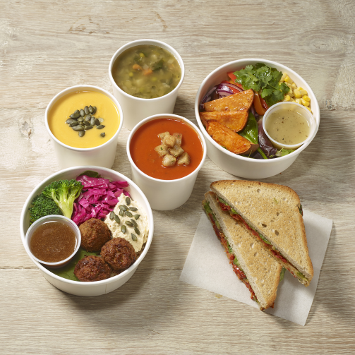 A table with bowls of soup, sandwiches, and a sandwich.