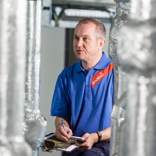 A worker is taking notes among vertical silver pipes