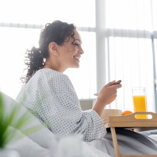 Female patient is eating in her hospital bed, holding a spoon