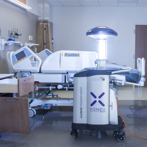 A cleaning robot next to a hospital bed