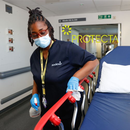 A member of the Sodexo team cleaning an empty bed in a hospital corridor before it is used on a ward.