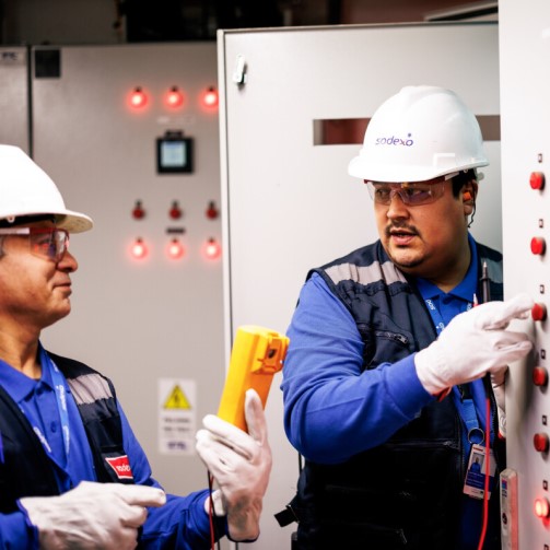 One worker is taking a reading of the device he is holding and talking to his colleague