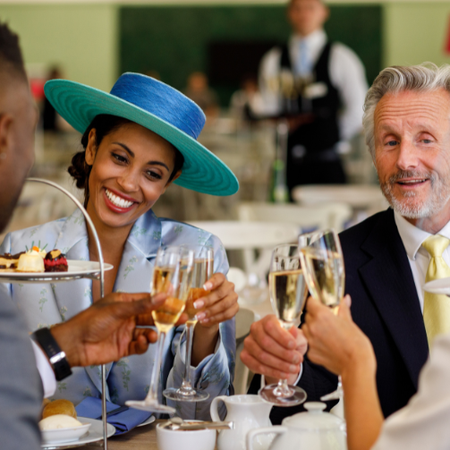 A couple of guests enjoying fine dining at Royal Ascot and toasting with champagne 