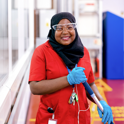 A woman in a red shirt and blue gloves standing outdoors