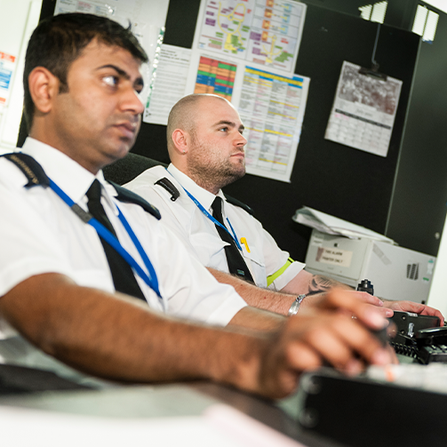 Two men in white shirts standing next to each other in front of their computers
