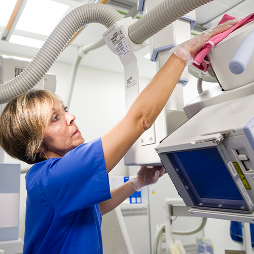 A woman in a blue shirt diligently cleans a machine