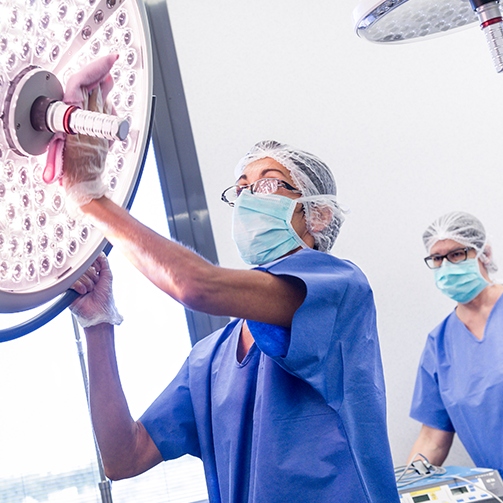 Two medical professionals in scrubs examining a bright light in a hospital room