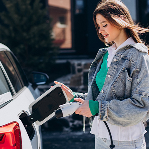 A woman charging her car at an electric vehicle charging station