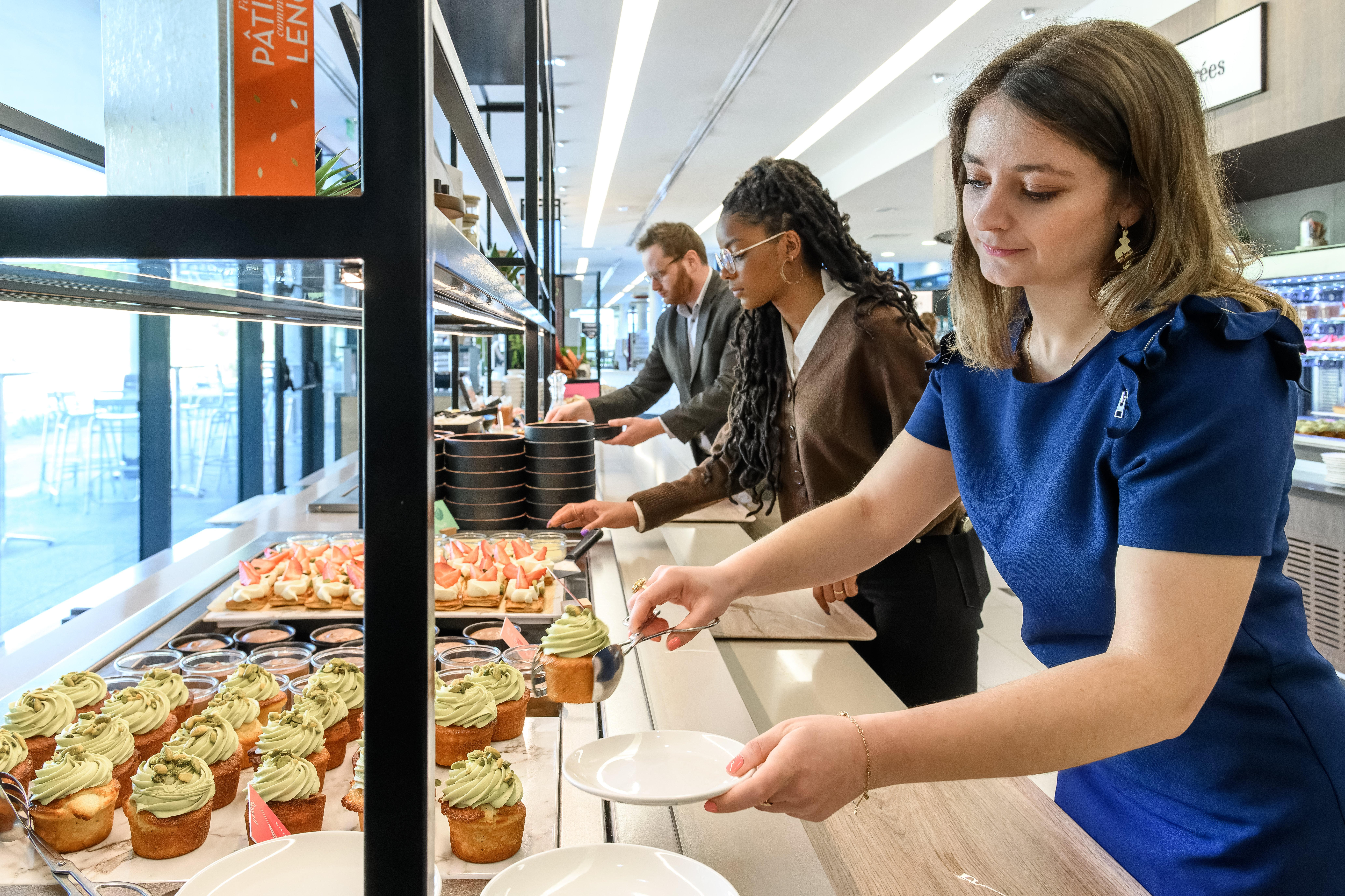 A woman serving food to a man at a buffet, offering a variety of dishes for him to choose from