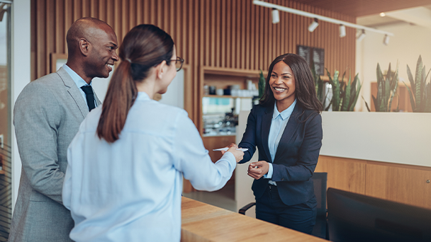 A woman givinga piece of paper to guests at a reception desk