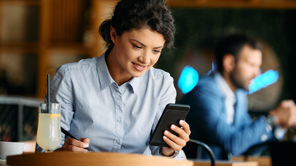 A woman sitting at a table, fiddling in her phone