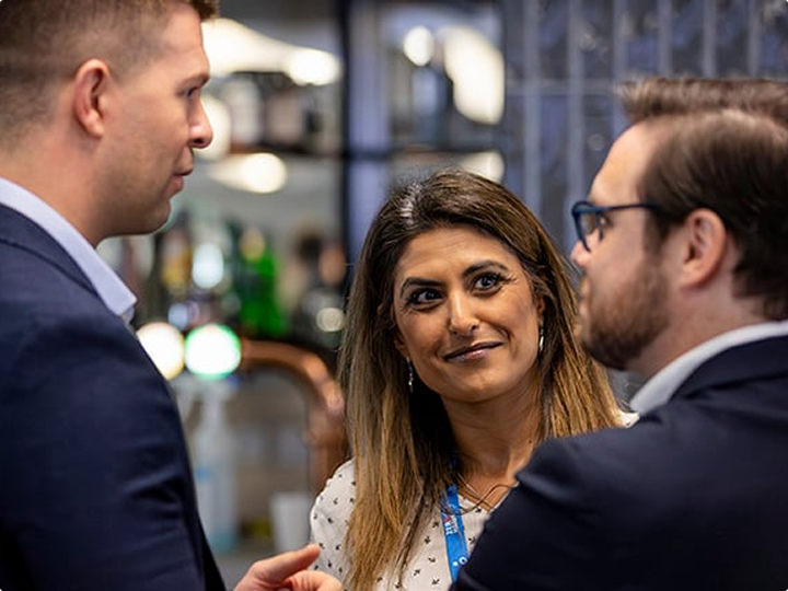 Three people standing together in conversation at an indoor event or gathering