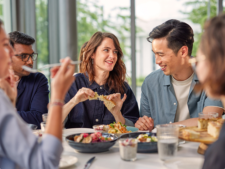 A group of people sitting together at a table sharing a meal, with various dishes and drinks in front of them