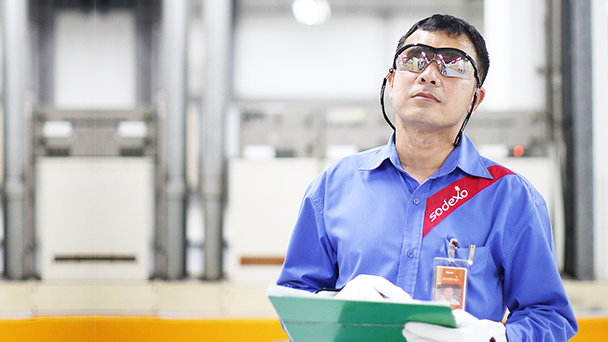 A man in safety glasses holding a clipboard