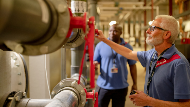 A man in a blue shirt and glasses standing next to a pipe