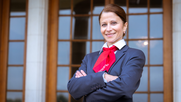 A woman in a suit and red tie posing outside