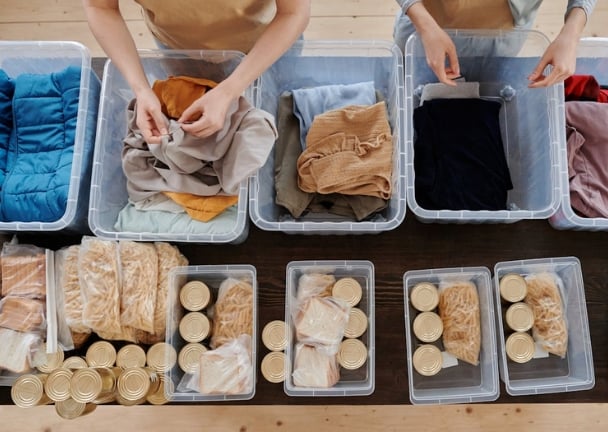 Hnads of two women organizing clothes and food in plastic bins