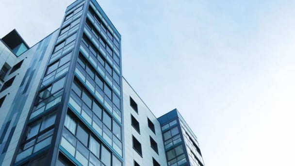 A towering building with numerous windows against a backdrop of a clear blue sky