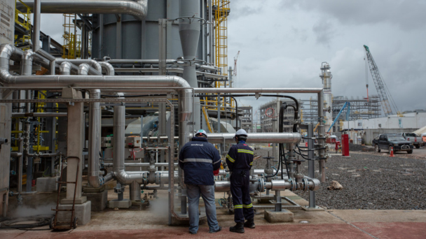 Two men standing in front of pipes in an industrial sites