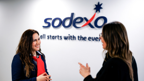 Women speaking in front of Sodexo logo