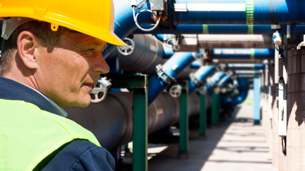 A man in a hard hat inspecting pipes at a construction site