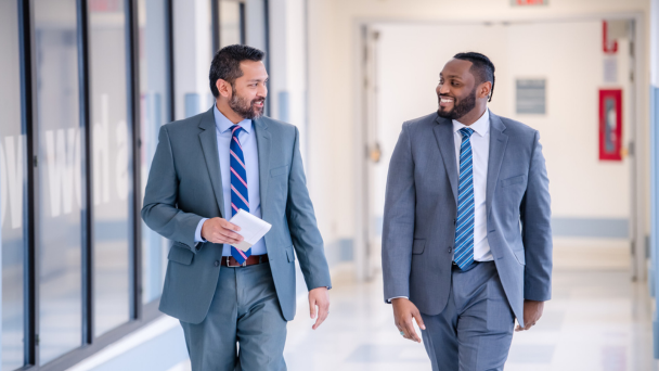 A smiling man with a beard wearing a blue jacket