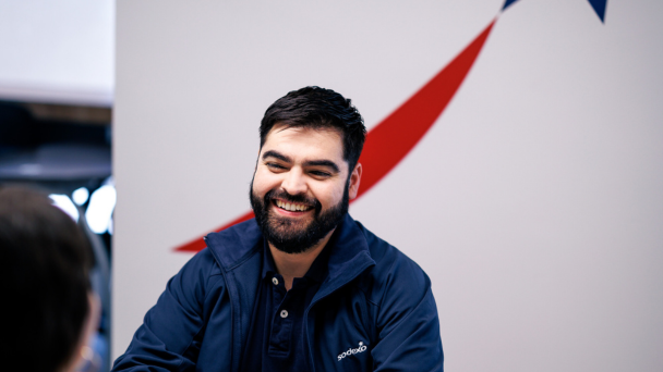 A smiling man with a beard wearing a blue jacket