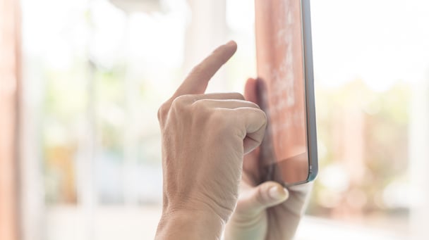 Hands of a person using a tablet computer with their finger to interact with the screen.