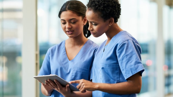 Two female nurses are looking at a tablet