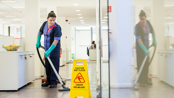A woman diligently mops the floor with a wet mop, ensuring cleanliness and hygiene