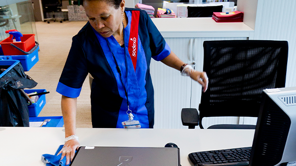 A woman wiping a laptop screen with a microfiber cloth, removing dust and fingerprints