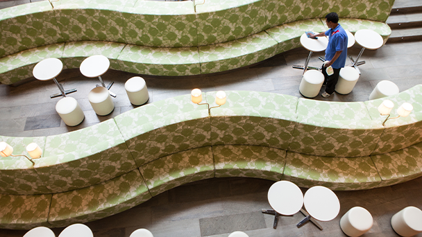 A man cleaning a restaurant, surrounded by tables and chairs